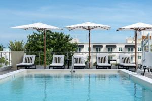 迈阿密海滩Nassau Suite South Beach, an All Suite Hotel的一个带椅子和遮阳伞的游泳池