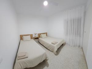 卡拉瓦卡·德·拉·克鲁斯Apartamento Gómez的配有2张床的白色墙壁和窗帘