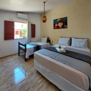杰里科科拉Na Casa Delas Jericoacoara的酒店客房设有两张床,墙上有一位女士