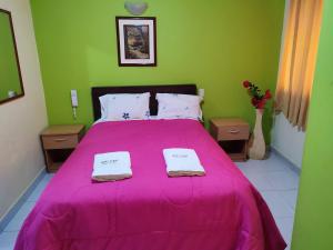 阿亚库乔Hotel Misky Samay的一间卧室配有粉红色的床和2条毛巾