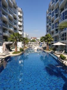 芭堤雅市中心Grand Avenue Pattaya的一座大型游泳池,位于部分建筑前