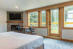 班夫Hotel Canoe and Suites的卧室配有一张床、壁炉和窗户。