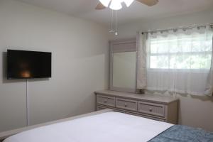 莱克兰Hidden Sapphire-Apartment with Kitchen and Laundry的一间卧室设有一张床、一台电视和一个窗口。