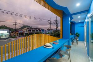 甲米镇Otter House Aonang Intersection的蓝色的阳台,配有带帽子的桌子