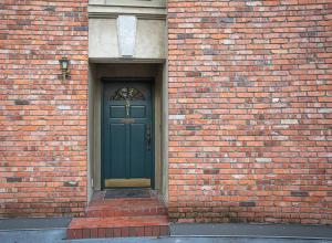 温哥华Historic Townhouse in Kitsilano的砖砌建筑的绿色门,有人行道