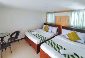 科隆RedDoorz @ Recson Hostel Coron Palawan的酒店客房,设有两张床和一张桌子及椅子