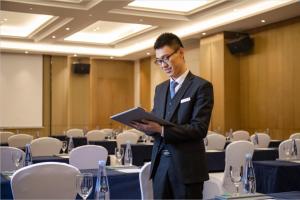萍乡萍乡武功山万达锦华酒店的身着西装的人站在一个桌子房间里
