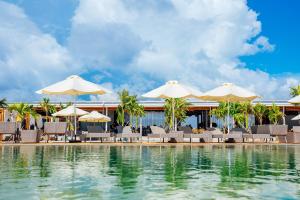 西哈努克Summer Bay Beach Club & Cabins的一个带椅子和遮阳伞的游泳池的度假酒店