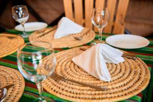 阿鲁沙freedom inn的一张桌子,上面放有柳条盘子和餐巾,还有酒杯
