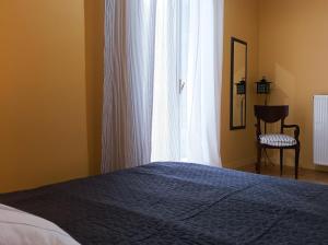 雅典Beautiful house in Chalandri的一间卧室设有一张床、一个窗口和一把椅子