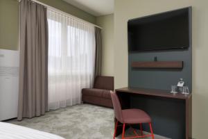阿劳b-smart hotel Schönenwerd的酒店客房配有一张床、一张书桌和一台电视。