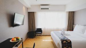 查亚普拉Hotel Suni Sentani的酒店客房设有一张床和一张带果盘的桌子。