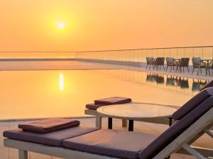 科威特Arabella Beach Hotel Kuwait Vignette Collection, an IHG Hotel的游泳池前设有桌椅