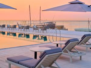 科威特Arabella Beach Hotel Kuwait Vignette Collection, an IHG Hotel的一组椅子和桌子,位于游泳池旁