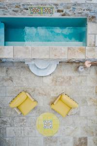 埃尔莫波利斯Aristide Hotel - Small Luxury Hotels of the World的享有游泳池的顶部景致,设有黄色座椅。