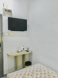 新山Kozi Hotel - Bukit Indah的一间设有桌子的房间和墙上的电视