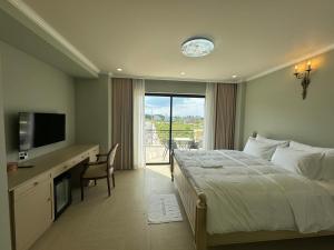 Phú MỹAn Nhiên Villa Hotel的一间卧室配有一张床和一张书桌及电视
