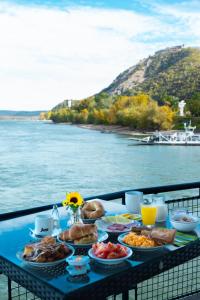 维谢格拉德Aquamarina Hotel Visegrád的一张蓝色桌子,上面有食物,放在水边