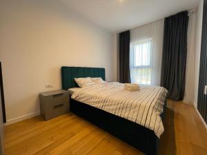 布加勒斯特UpNorth Home的一间卧室配有一张带绿色床头板的床和窗户