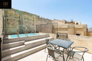 姆迪纳Historical Mdina Gem, Lux HOME with Rooftop Pool by 360 Estates的一个带游泳池的阳台的桌椅