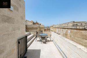 姆迪纳Historical Mdina Gem, Lux HOME with Rooftop Pool by 360 Estates的墙上设有带桌椅的阳台