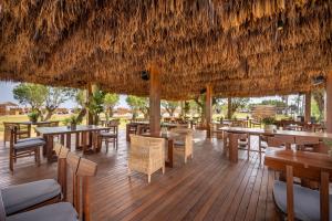 蒂加基Ananea More Meni Kos ex More Meni Beach的一间带桌椅和稻草屋顶的餐厅