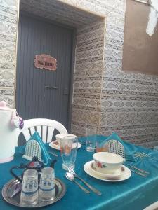 提兹尼特Grotte de pêcheurs RITAJ, Aglou的一张桌子,上面有蓝桌布,上面有盘子和眼镜