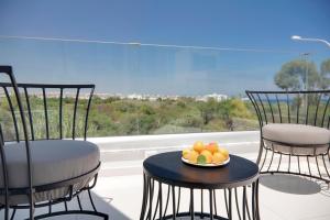 普罗塔拉斯Sunrise Seaview Villas的阳台上的桌子上放着两把椅子和一盘水果