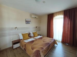 普里莫尔斯科Семеен Хотел Детелини的酒店客房配有一张带黄色枕头的大床