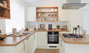 纽基Newperran Holiday Park的厨房配有白色橱柜和炉灶烤箱。