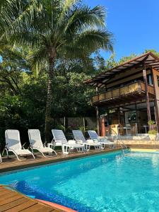 伊利亚贝拉Moana Ilhabela的一个带躺椅的游泳池和一个棕榈树房子