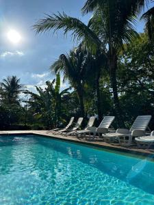 伊利亚贝拉Moana Ilhabela的一组椅子和一个棕榈树游泳池