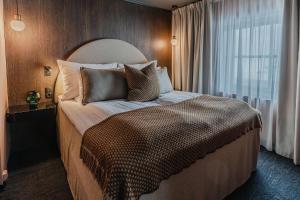 朗伊尔城方垦小屋酒店的卧室配有带枕头的大床和窗户。