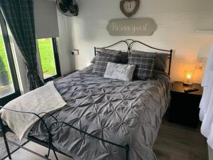 圣亚萨Dolafon farm luxury glamping cabin with hot tub的一间卧室配有一张带灰色棉被和枕头的床
