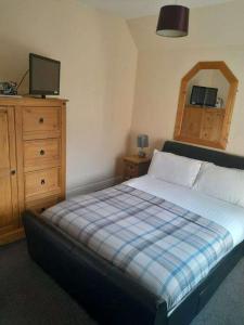 NewcastletonThe Grapes Hotel的一间卧室配有一张床、一个梳妆台和电视。
