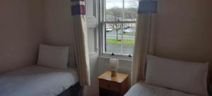 NewcastletonThe Grapes Hotel的带窗户的客房内设有两张单人床。