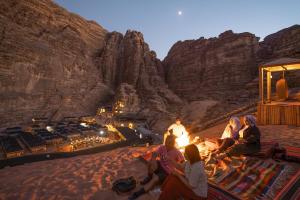 瓦迪拉姆迎宾沙漠营地酒店的一群人坐在沙漠的火堆旁
