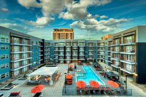 凤凰城Cozysuites PHX RORO Gym, Pool, Pets, Parking! #3的公寓大楼设有游泳池和橙色遮阳伞
