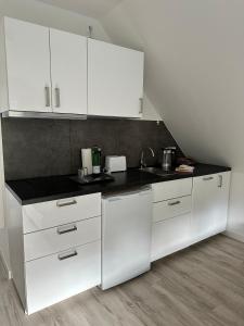 汉堡Lagom - Apartments an der Barclays Arena的厨房配有白色橱柜和黑色台面