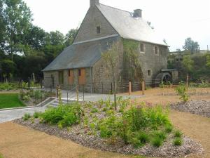 PratGite Du Moulin Du Poulloguer的一座古老的石头谷仓,前面设有一个花园