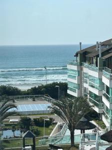 弗洛里亚诺波利斯Praia do Santinho, de frente para mar的一座带网球场的建筑,毗邻大海