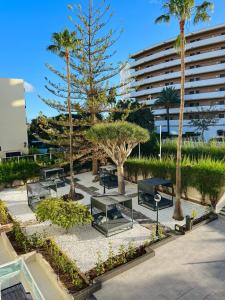 英格兰海滩Apartamentos Fayna的一个带长椅和棕榈树的公园和一座建筑