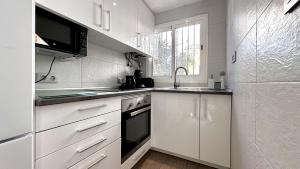 贝尼多姆Bungalow Playa Poniente Benidorm的白色的厨房配有水槽和冰箱