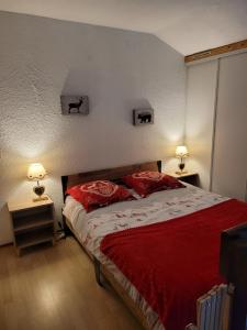 莱鲁斯Le Chalet, Superbe Duplex 3 étoiles proche du centre des Rousses, 5 personnes, Draps inclus的一间卧室配有一张带红色床单的床和两盏灯。