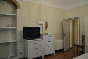普拉托Appartamento Guido的一间白色梳妆台上配有电视的卧室