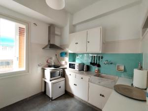 雅典生活超便利的小公寓的厨房配有白色橱柜和窗户。