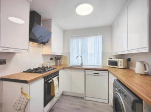 曼彻斯特Regent House - Modern Holiday Home 10 Minutes to Manchester City Centre With Free Parking的厨房配有白色橱柜、洗衣机和烘干机