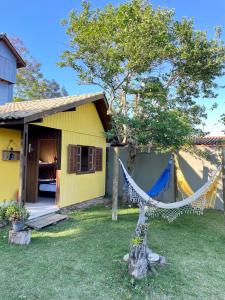 普腊亚罗萨Pousada Lua de Java - Casa Bali的黄色房子前面设有吊床