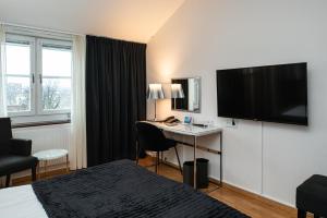 胡迪克斯瓦尔斯塔特优质酒店的酒店客房配有一张床和一张书桌及一台电视