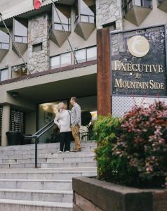 惠斯勒惠斯勒山边公寓式酒店的站在建筑物外台阶上的男女
